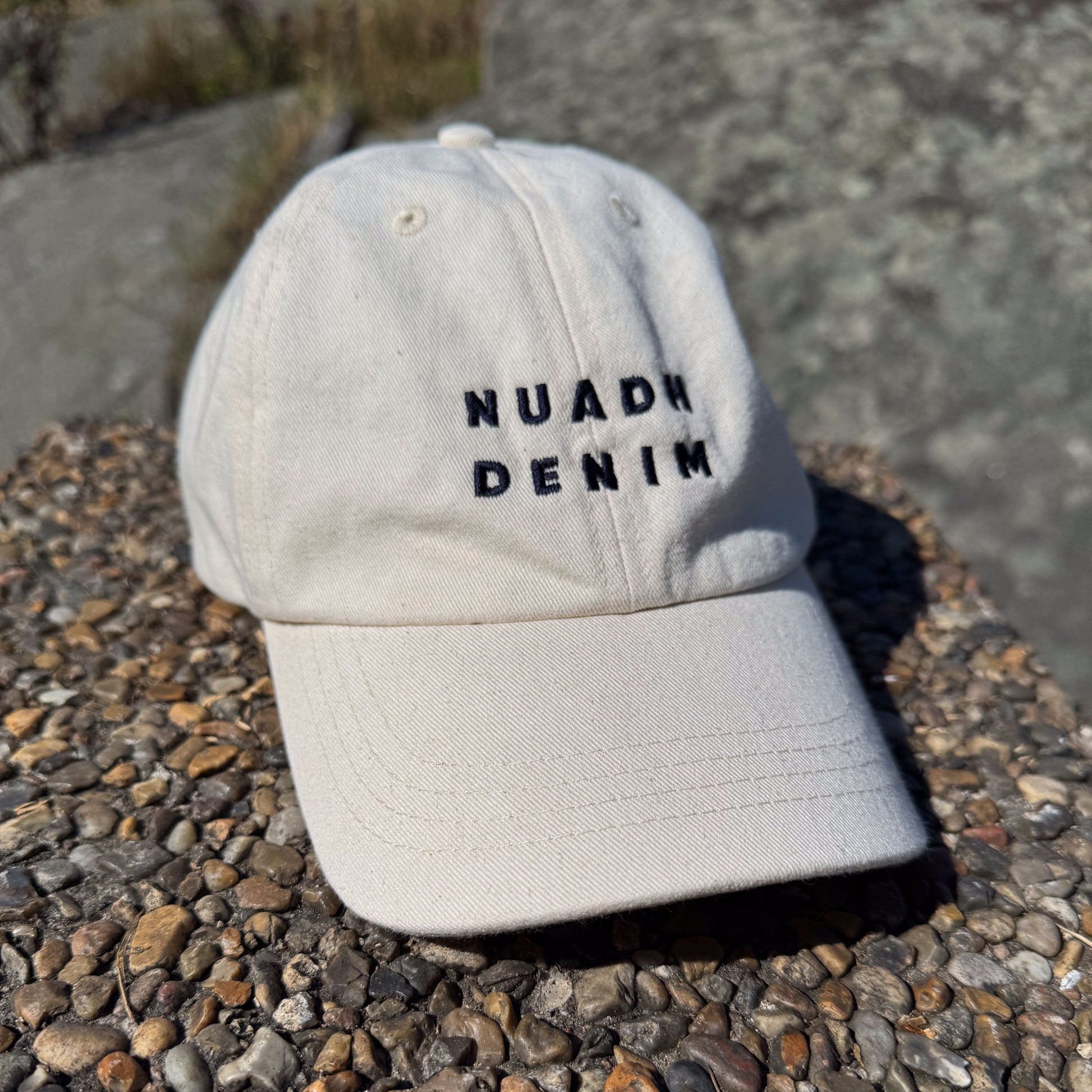 NUADH DENIM Six-panel baseball cap crafted from unbleached natural cotton twill with self coloured topstitching. Embroidered NUADH DENIM logo on the front panel. 
Six-paneled Soft unstructured crown. 
NUADH DENIM | Catacol Bay Dad cap | 100% Organic unbleached cotton| Made in Scotland.