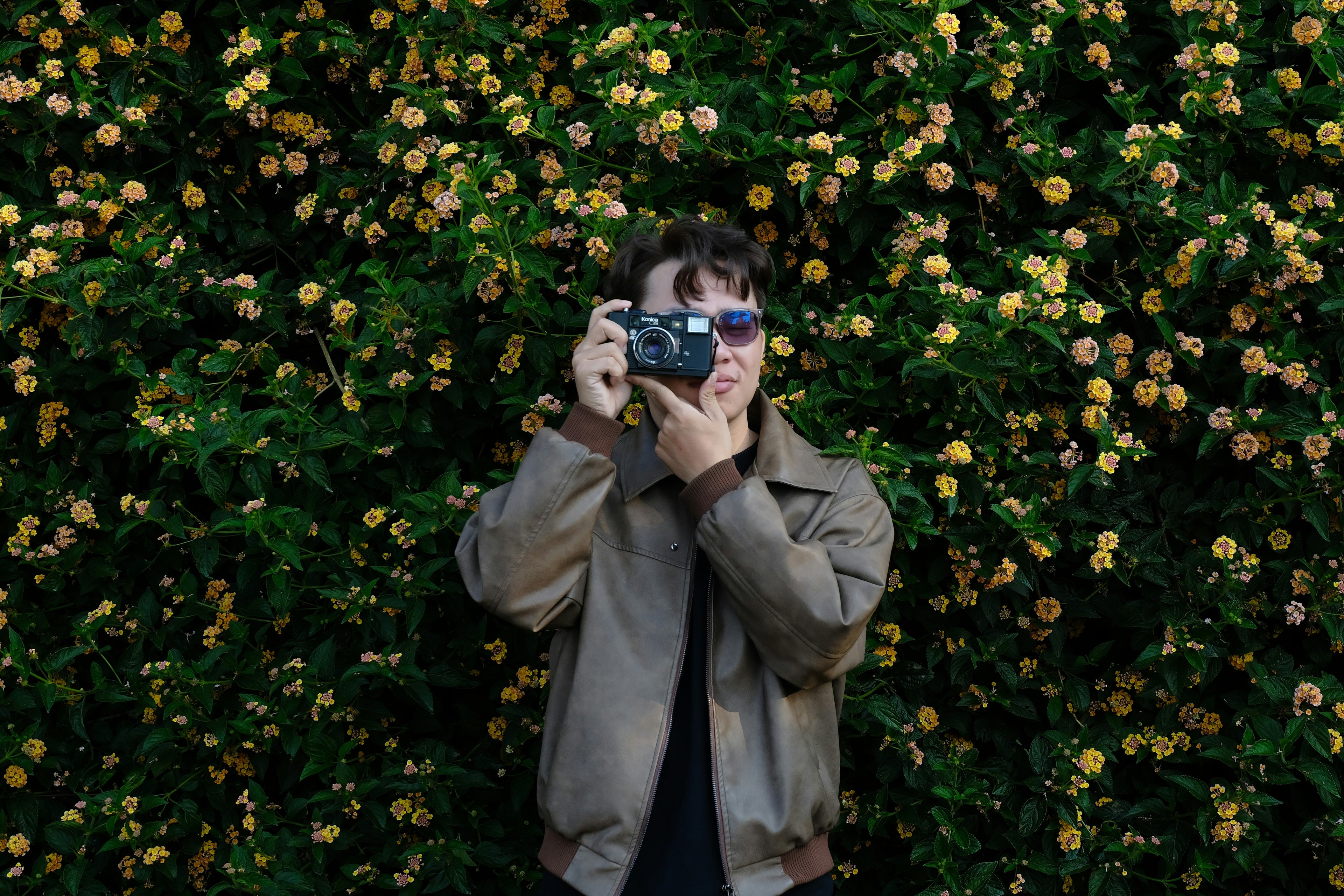Person taking a photo with a camera against a floral background