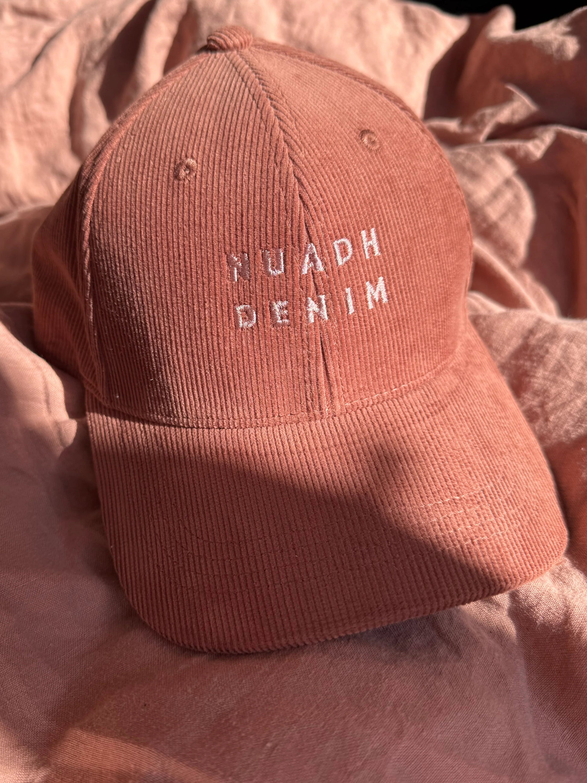 close up of NUADH DENIM - Sannox bay 6 panel surfer cap - cord fabric -  Pink - redwood colour with tonal lighter rose NUADH denim logo embroidery.