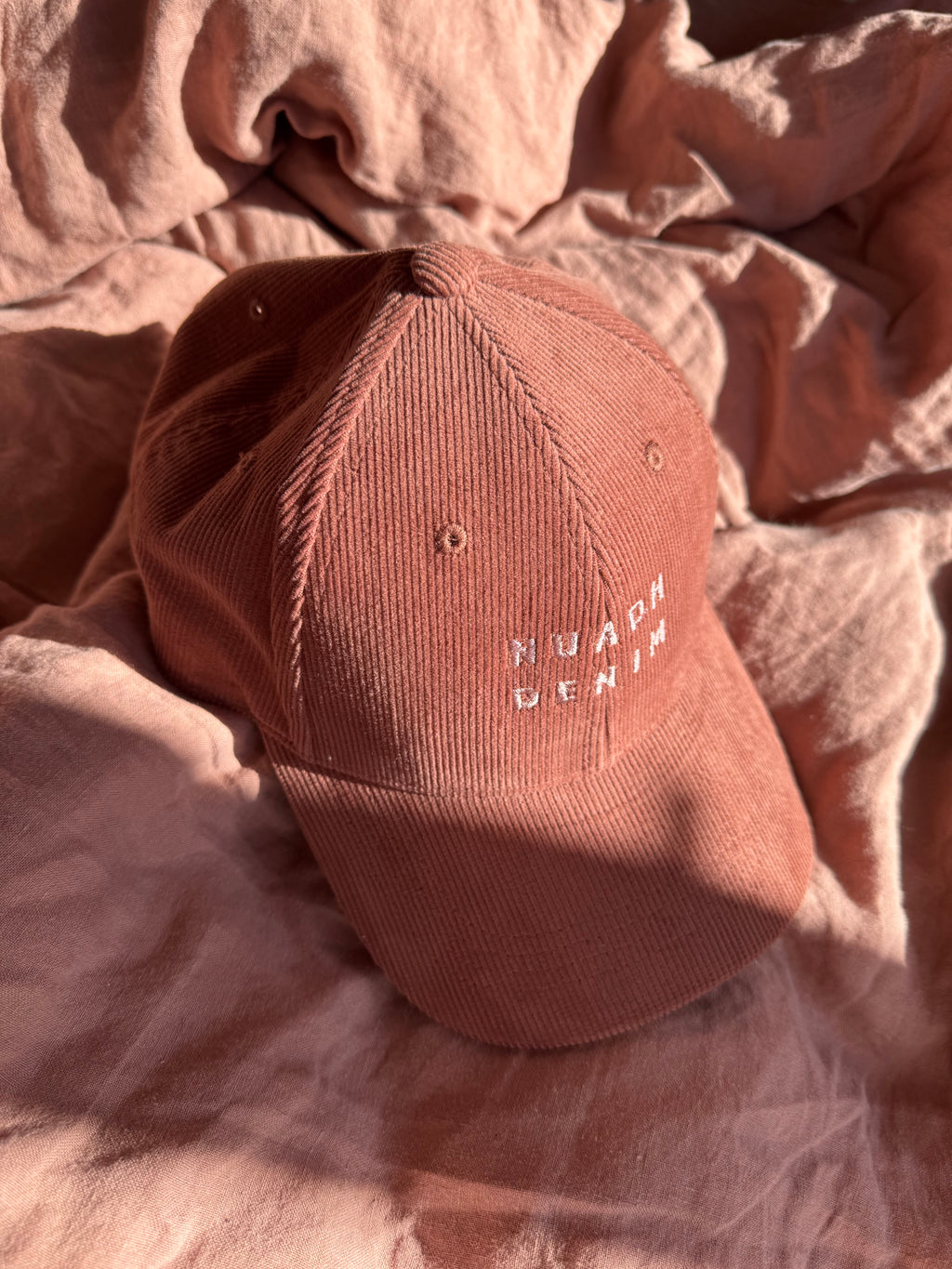 close up of NUADH DENIM - Sannox bay 6 panel surfer cap - cord fabric -  Pink - redwood colour with tonal lighter rose NUADH denim logo embroidery.