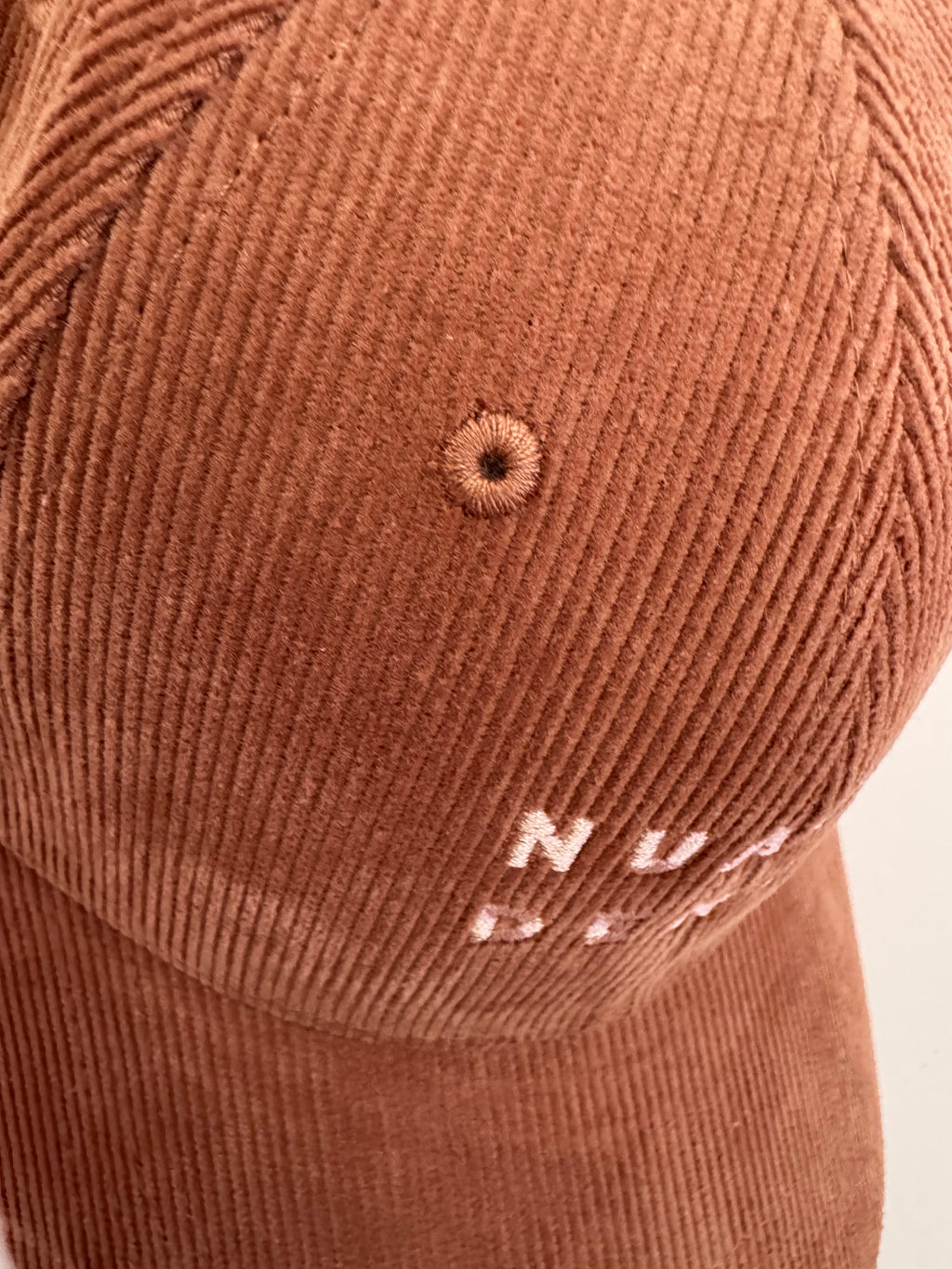 close up of NUADH DENIM - Sannox bay 6 panel surfer cap - cord fabric -  Pink - redwood colour with tonal lighter rose NUADH denim logo embroidery.