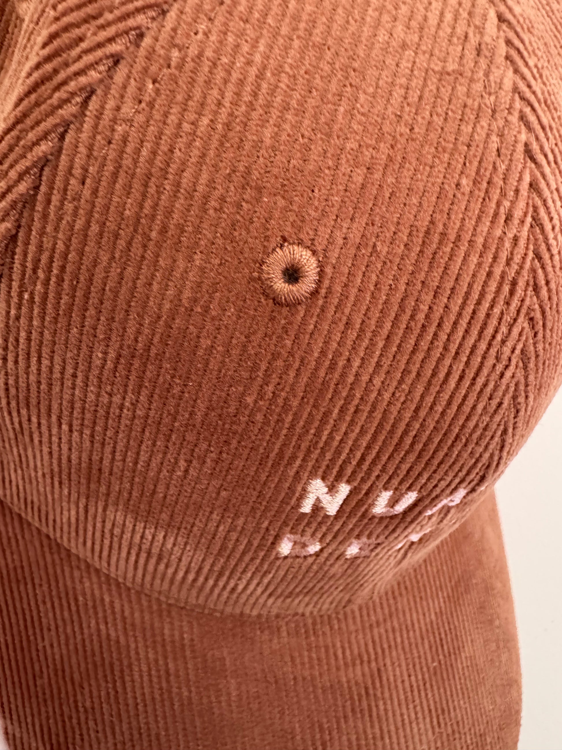 close up of NUADH DENIM - Sannox bay 6 panel surfer cap - cord fabric -  Pink - redwood colour with tonal lighter rose NUADH denim logo embroidery.