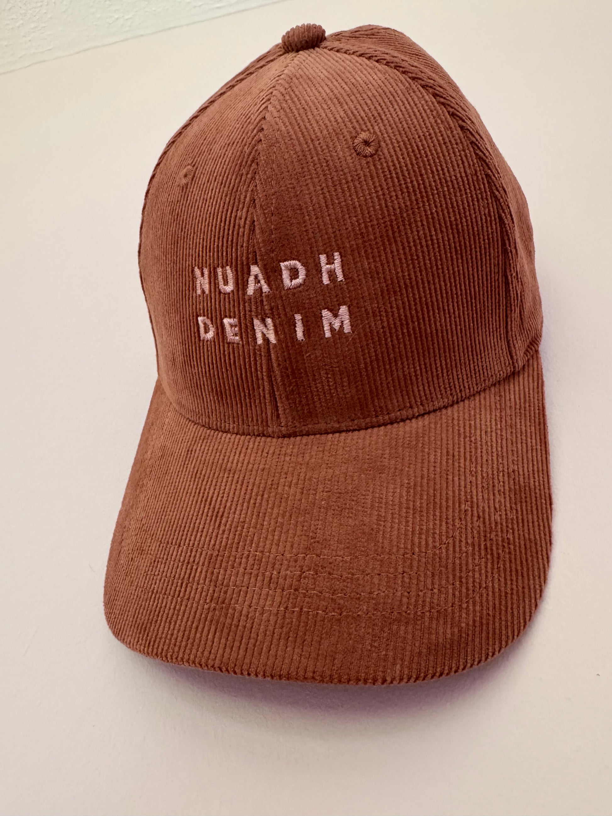 close up of NUADH DENIM - Sannox bay 6 panel surfer cap - cord fabric -  Pink - redwood colour with tonal lighter rose NUADH denim logo embroidery.