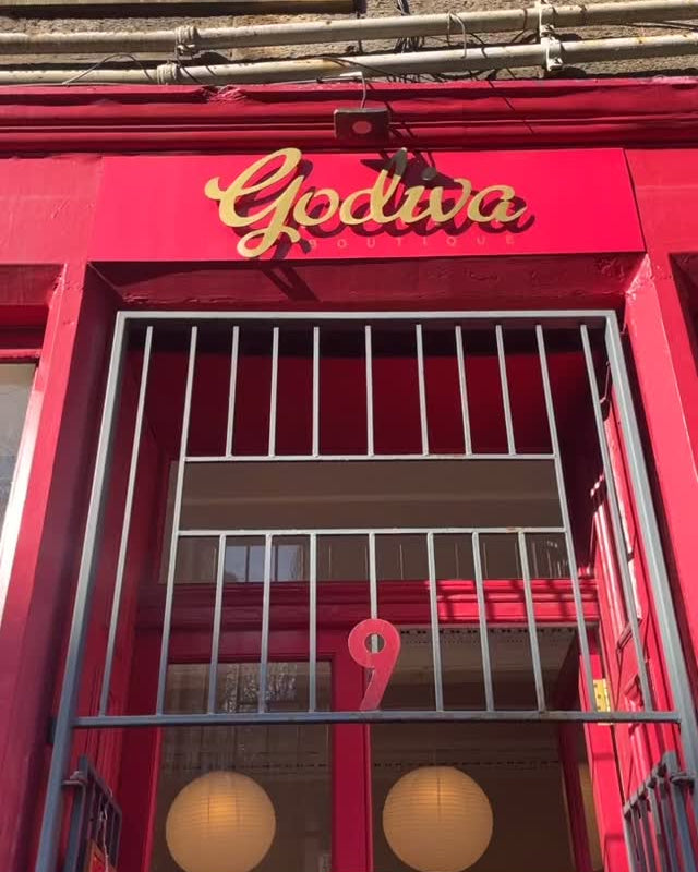 A storefront facade with a bright pink Godiva sign in gold lettering above a metal security gate. The building has a stone facade, and a pink door and window frames.

NUADH DENIM is now in stock at Godiva, Edinburgh, 9 West Port, Edinburgh EH1 , Scotland